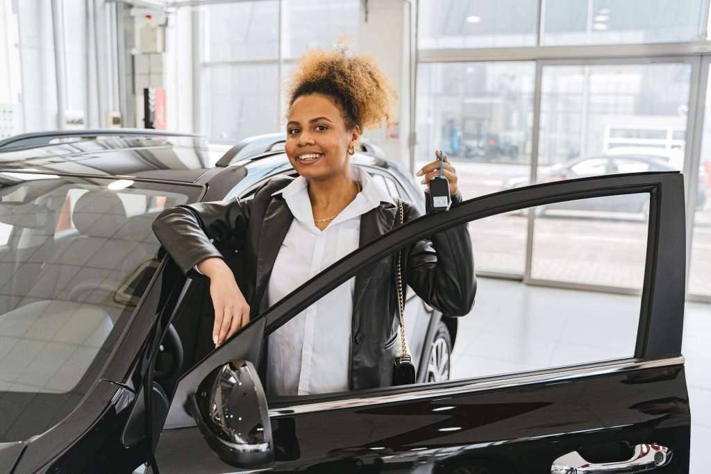 A woman standing next to a showroom when buying a new car