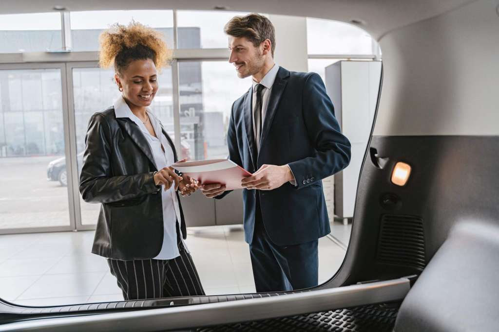 a man and a woman standing in front of a car.