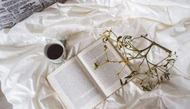 An open book and a cup of coffee on a Murphy bed.