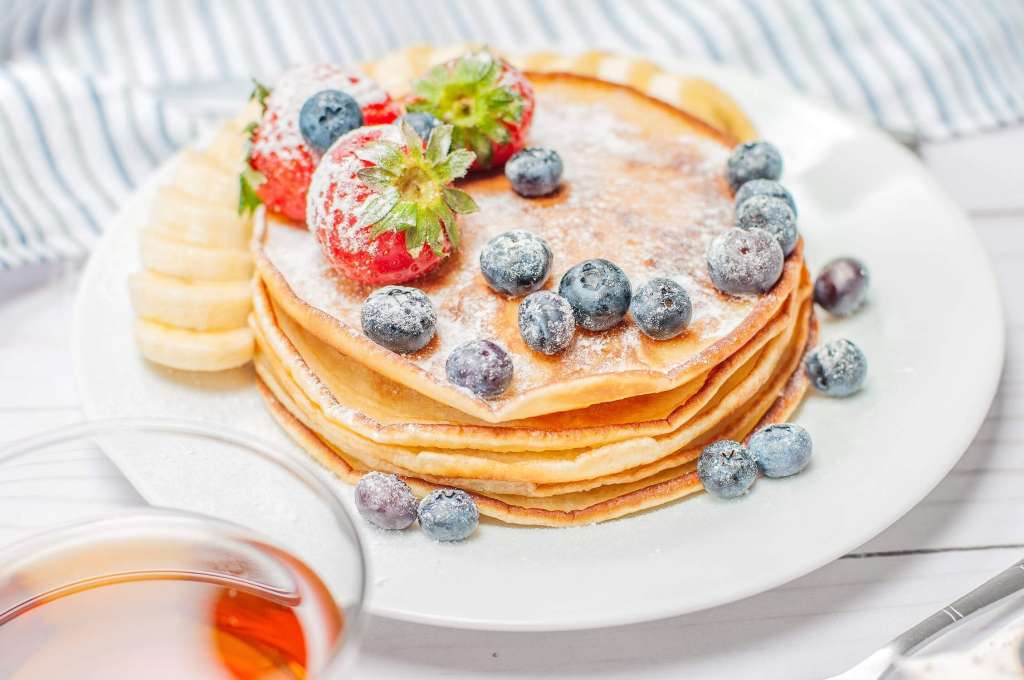 a stack of pancakes topped with blueberries and strawberries.