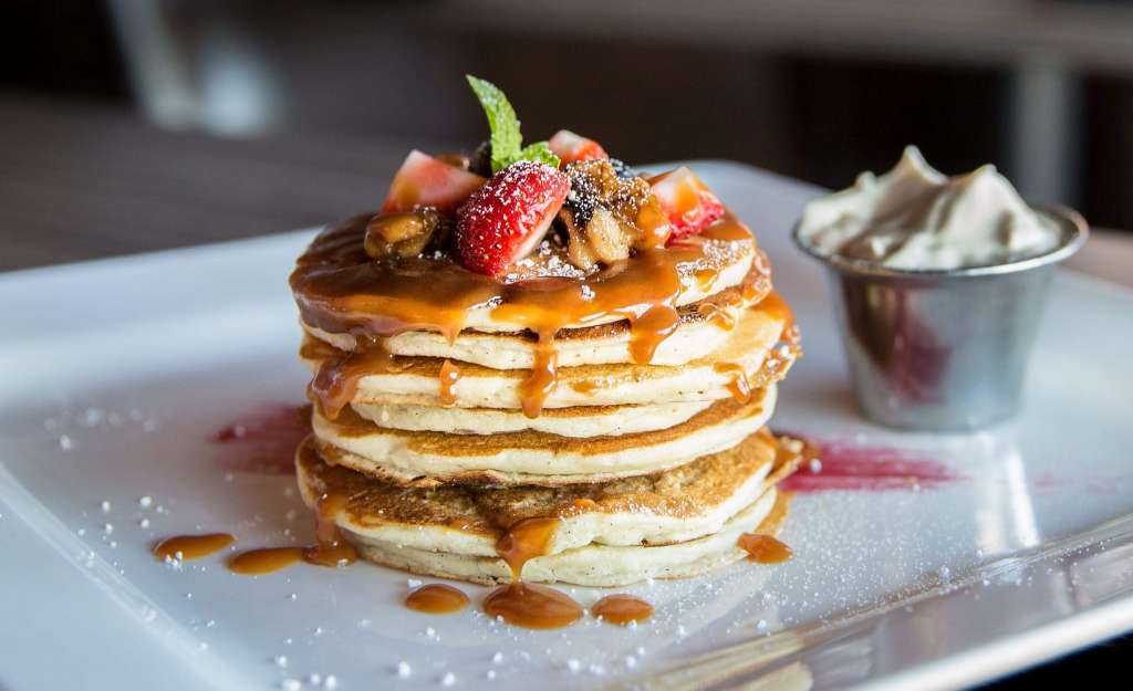 a stack of pancakes topped with fruit and syrup.