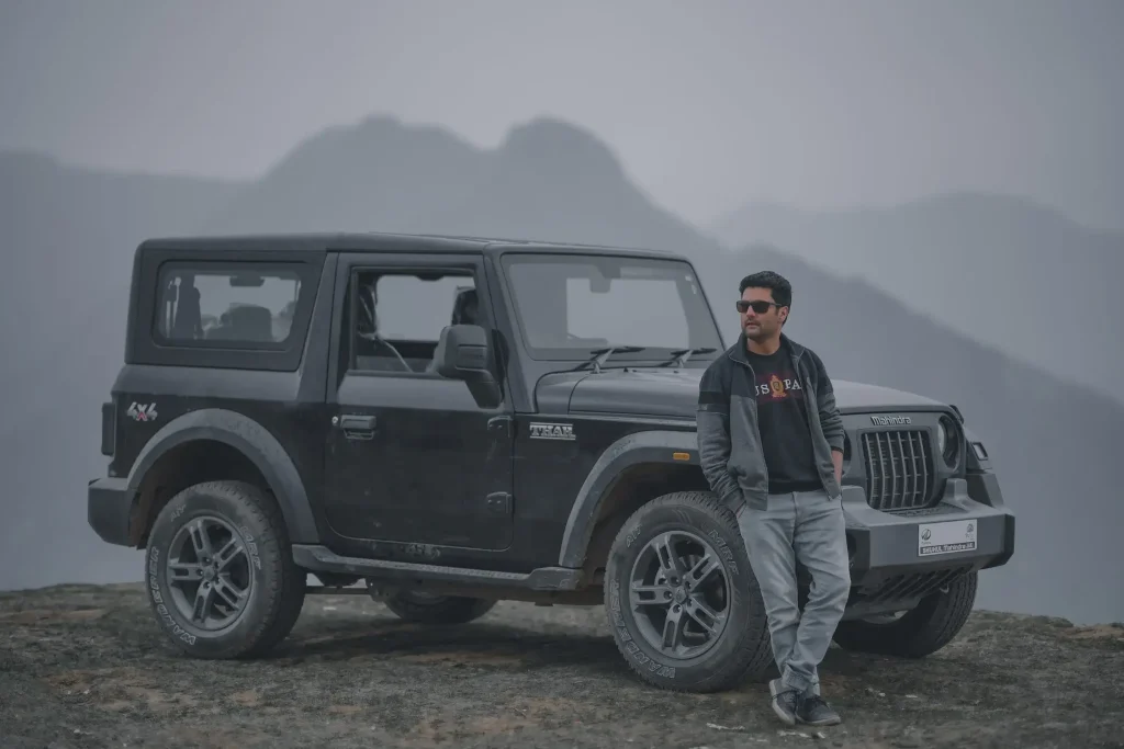 A man standing in front of a parked Jeep vehicle 

