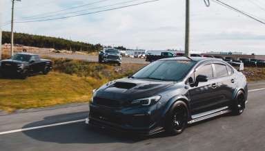 A black car riding on a paved road